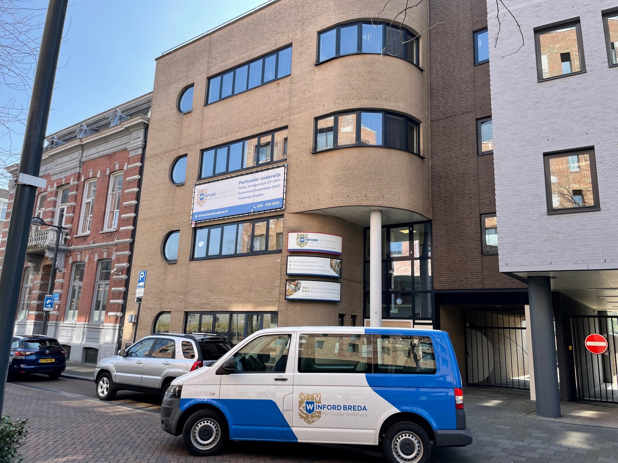 Het schoolgebouw in Breda aan het stationsplein met een busje ervoor.